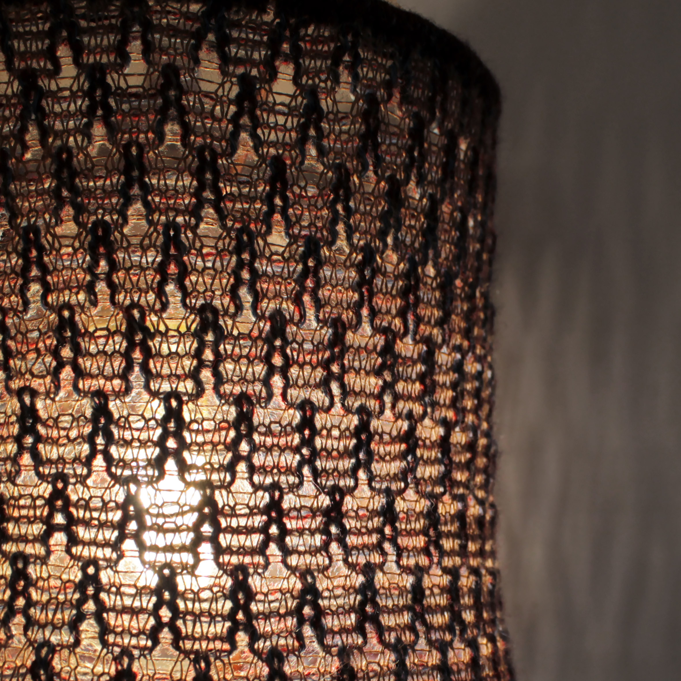 Détail d'une lampe d'appoint baladeuse à suspendre en maille, tricot de laine. Suspension design artisanale et fait main.